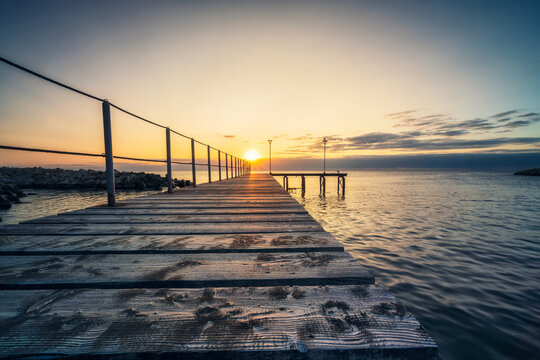 Rising sun above wooden bridge at sea coast
