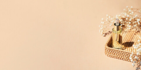 Transparent bottle with dropper pipette in a wicker basket. Beige background daylight and beautiful...