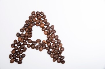 A is a capital letter of the English alphabet made up of natural roasted coffee beans that lie on a white background. Plenty of space to put text or pictures, top view and studio photography.
