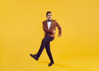 Funny young black man dancing isolated on a yellow colour background. Full length shot of a happy...