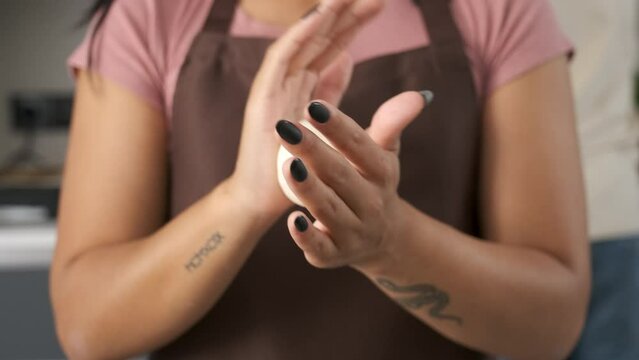 Young unrecognizable Venezuelan woman moulding the dough into a arepa at kitchen.