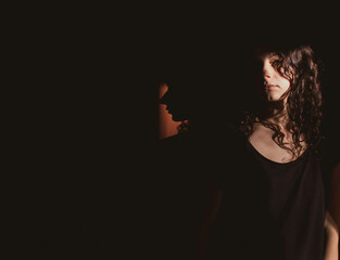 young woman on black background with light and shadow on face