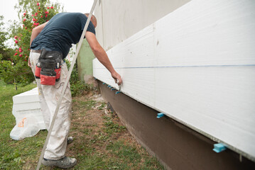 Construction worker removing excess of glue from isolation boards