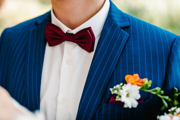Groom in blue suit and white shirt with boutonniere on nature background. Close up. - obrazy, fototapety, plakaty