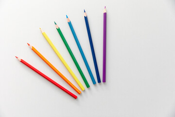 Top view Minimal design of open Notebook with colored pencils of rainbow colors on white background with blank space. Flat lay