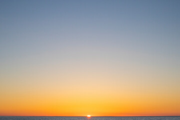 Naklejka premium Orange sun setting over lake