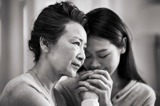 young asian daughter comforting elderly mother