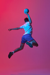 Back view. Dynamic studio shot of professional male handball player in motion training, playing isolated on gradient pink background in neon light. Concept of sport, action, motion, sportive lifestyle
