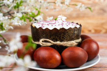 Festive Easter composition with Easter cake, colored eggs and blossoming cherry branches. Easter card. Close-up. Selective focus.