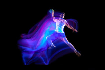 Throwing ball in a jump. Young man, professional handball player in motion, playing over black...
