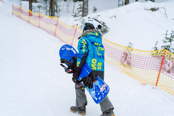 little boy learning to ride on snowboard standing on ski slope. Winter leisure.