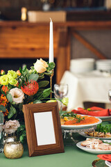 An empty wooden frame on a festive table in a restaurant, a place for your mockup