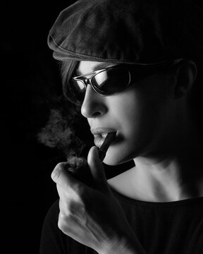 Atractive young woman smoking a vintage wooden pipe. Monochrome portrait isolated on black with copyspace