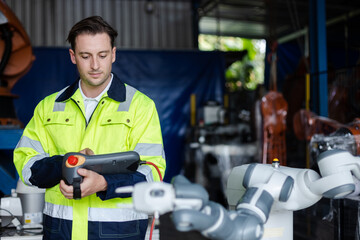 man engineer using remote robot controller operate standing at automation robot arms machine in...