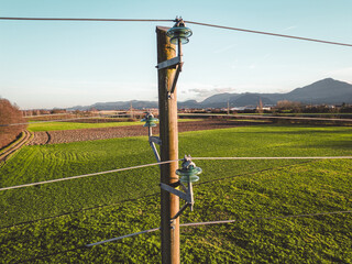 Close up of an old electrical tower with electrical wire running to and from it 