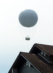 Fototapeta na wymiar A hot air balloon floats above the roof.