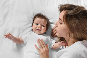 Mother calming crying daughter on bed, top view