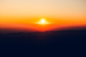 drone view from the top of a mountain with a beautiful sunset with the sky completely orange and red without any clouds in horizontal