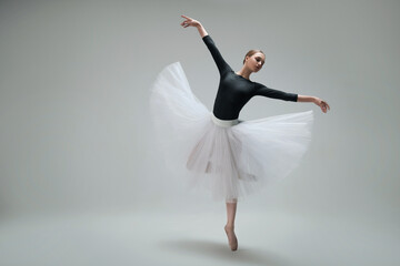 Young ballerina practicing dance moves on light grey background. Space for text