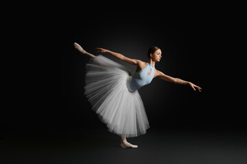 Young ballerina practicing dance moves on black background - obrazy, fototapety, plakaty