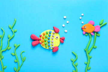 Seaweed and fish made of plasticine on light blue background, flat lay