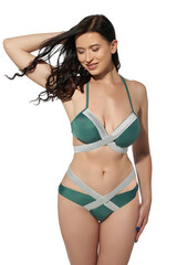 Obraz premium A lady is wearing a two-piece gray and green swimsuit with silver ribbons composed of low-rise bikinis and a bra with a neck strap. The slim woman in the swimwear is posing on a white background.