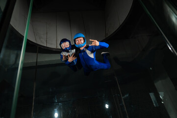 A man teaches a boy to fly in a wind tunnel. Lack of gravity.