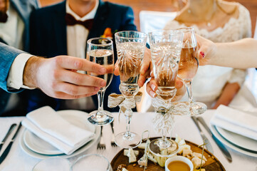 Cheers! People celebrate and raise glasses of wine for toast. Group of man and woman cheering with champagne. Wedding guests in the banquet area.