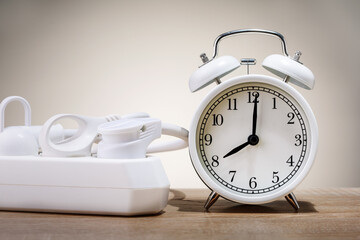 Electrical plugs with alarm clockon desk, saving energy concept. time to turn off the power.