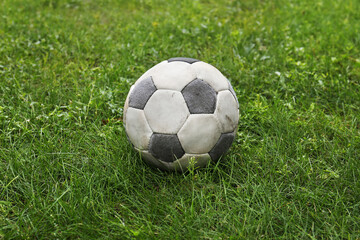 Fototapeta na wymiar Dirty soccer ball on fresh green grass outdoors