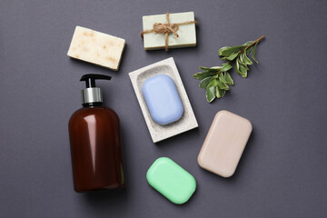 Soap bars and bottle dispenser on black background, flat lay