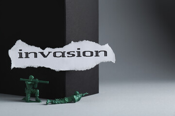 Paper with word Invasion and toy soldiers on light grey background. Space for text