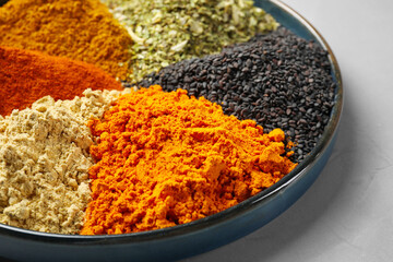 Plate with different spices on light grey table, closeup