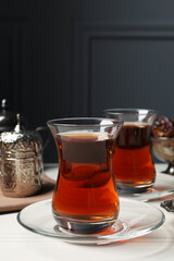 Glasses of tea and vintage tea set on white wooden table