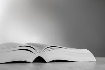 Open Bible on light gray table, space for text. Christian religious book