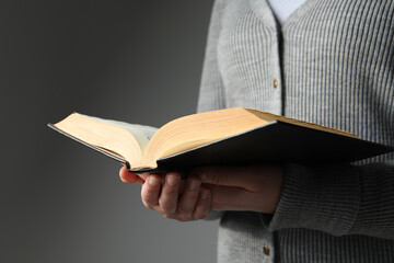 Woman reading Bible against grey background, closeup
