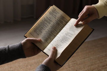Naklejka premium Woman showing psalm in Bible to man indoors, closeup