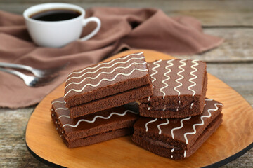 Tasty chocolate sponge cakes and hot drink on wooden table, closeup