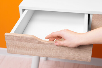 Woman opening empty desk drawer indoors, closeup