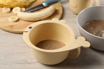 Baby food. Bowls with banana puree on light wooden table