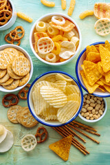 Salty snacks, shot from the top. A table of assorted appetizers in bowls, a flat lay of party food on teal blue