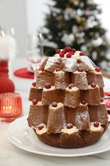 Delicious Pandoro Christmas tree cake decorated with powdered sugar and berries on white marble table