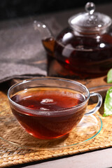 Aromatic hot tea in glass cup and teapot on table