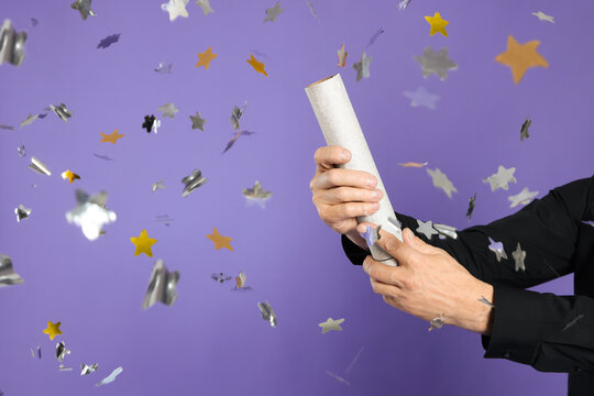 Man Blowing Up Party Popper On Purple Background, Closeup