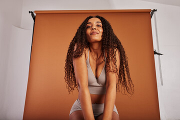 Young black with woman posing in underwear on an orange backdrop