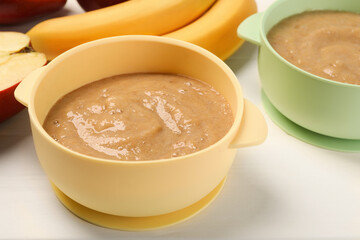 Bowls with banana puree on white table. Baby food