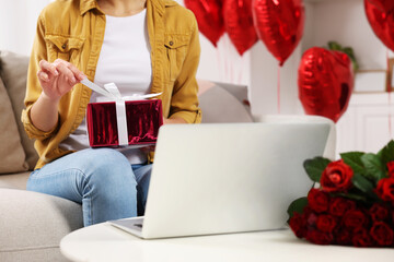 Valentine's day celebration in long distance relationship. Woman opening gift from her boyfriend at home, closeup