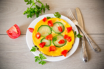 Fried omelet with zucchini, tomatoes, herbs in a plate