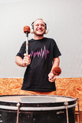 Smiling boy drumming with hearing protections inside a studio