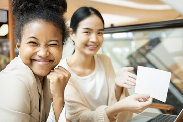 Team of young asian and african workers showing blank card with success